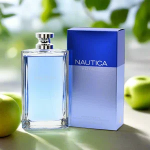 Parfumfles Nautica Voyage met lichtblauwe inhoud naast blauwe verpakking, omringd door groene appels en zachte natuurbokeh.