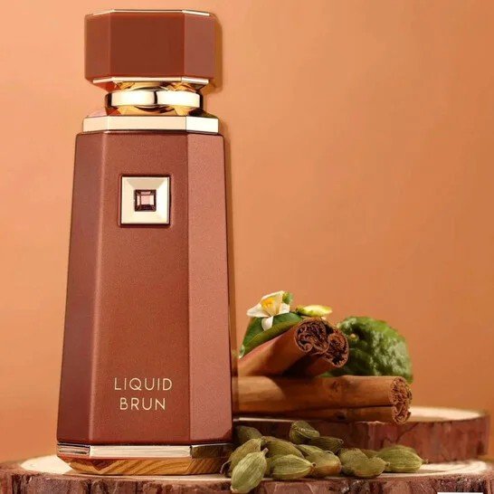 Luxe parfumfles Liquid Brun in bronskleur met gouden accenten, omringd door kaneelstokjes, kardemom en bergamot voor een warme en kruidige sfeer.